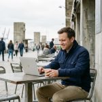 Jeune homme au café à Le Havre avec ordinateur et architecture moderne