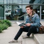 Jeune homme en denim avec sac photo et livre cinéma