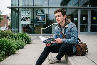 Jeune homme en denim avec sac photo et livre cinéma